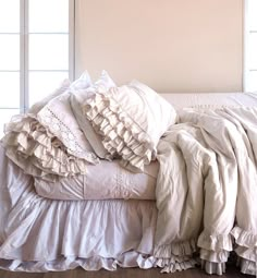 an unmade bed with ruffled sheets and pillows