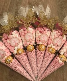 pink and gold candy cones are arranged in a pyramid on the floor with ribbons around them