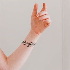 a woman's arm with a wristband that has an arrow tattoo on it