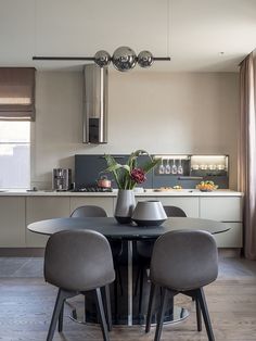 a dining room table with four chairs and a vase filled with flowers on top of it