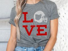 a woman sitting on a couch wearing a t - shirt that says love with a football helmet