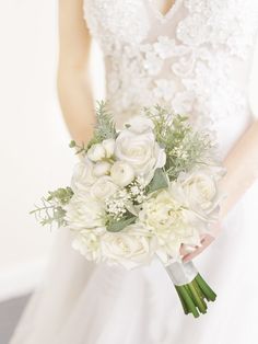 a bride holding a bouquet of white flowers