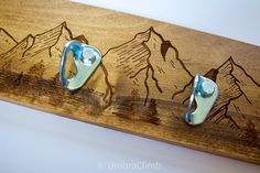 three metal hooks on a wooden board with mountains in the background