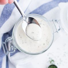 a spoon in a glass jar filled with white sauce on top of a blue and white towel