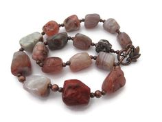 "Looking for a chunky agate necklace? This brown stone necklace necklace, rustic brownish red necklace may be the one. Created with Earth toned irregular stone nuggets in shades of brown, tan and red, copper spacer beads and an interesting copper toggle clasp, this 20\" beauty is unique. Channel your inner spirit and sport this russet necklace!  All items arrive in a pretty, satin drawstring, organza bag - perfect for gift giving! Interested in viewing more items? Please visit me at: JewelryJust Nugget Necklace, Brown Stone, Necklace Stone, Red Copper, Red Necklace, Necklace Necklace, Agate Necklace, Black Earrings, Toggle Clasp