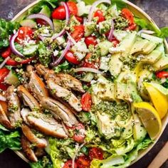 a salad with chicken, tomatoes, cucumber, onions and other veggies