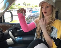 a woman sitting in the drivers seat of a car with her arm wrapped around another person's wrist