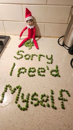 an elf is sitting on the counter with peas in front of him that says sorry feed me