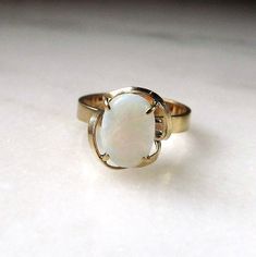 This is a vintage womens 14K yellow gold opal gemstone ring.  The band is sized at a 7.  The genuine opal gemstone measures 10mm long x 7mm wide.  Total weight of the ring is 3.0 grams.  The inside of the band is not marked, but we did test the karat quality of the gold.  It is 14K. This is a vintage, previously owned ring.  Therefore, light wear can be expected.  There is no visible damage. Formal Yellow Gold Ethiopian Opal Ring, Classic Opal Moonstone Ring As Gift, Heirloom Oval Opal Ring With Polished Finish, Vintage Opal Ring As A Gift, Classic Opal Moonstone Anniversary Ring, Classic Moonstone Opal Ring For Anniversary, Vintage Opal Jewelry For Anniversary, Elegant Ethiopian Opal Ring For Anniversary, Heirloom White Opal Ring Oval Cabochon