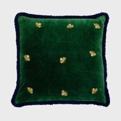 a green velvet pillow with gold bees on the front and blue trim around the edges