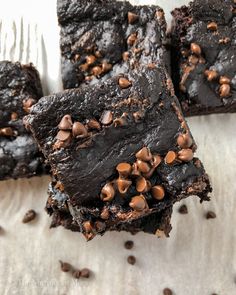 three chocolate brownies with chocolate chips on top and one has a bite taken out of it