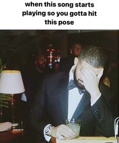 a man in a tuxedo is holding his face to his head while sitting at a table