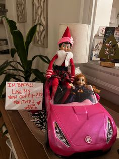 a pink toy car with an elf riding in it