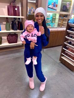 a woman holding a baby in her arms while standing next to a store display case