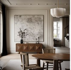 a dining room table with chairs and a painting on the wall