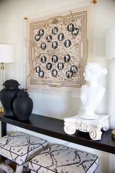 two vases are sitting on a shelf in front of a wall with an art work