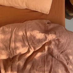 an unmade bed with pink sheets and pillows