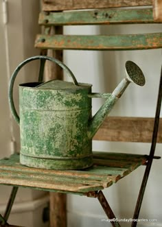 an old green watering can sitting on top of a chair