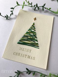 an embroidered christmas card with a green tree on it and the words merry christmas written in gold