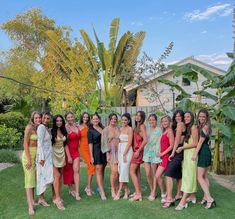 a group of women standing next to each other on top of a lush green field