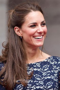 a woman with long hair smiling and wearing a blue dress