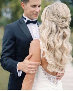 a man in a tuxedo standing next to a woman with long blonde hair