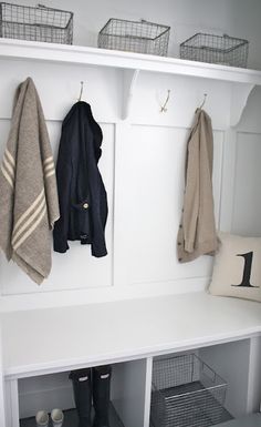 a coat rack with two coats hanging on it's sides and some shoes underneath