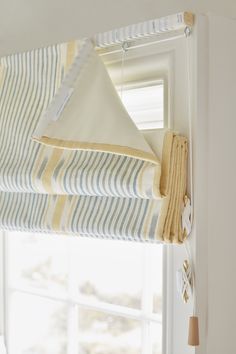 a white window with blue and yellow striped roman shades hanging from it's side