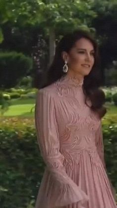 a woman in a pink dress is standing outside