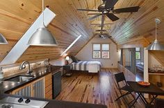 a kitchen and living room inside of a wooden cabin with ceiling fans on the ceiling