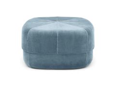 a blue ottoman that is sitting on the white floor and it's made out of fabric