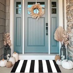 a blue front door with two pumpkins and a wreath