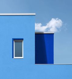 a blue building with a window and sky in the background