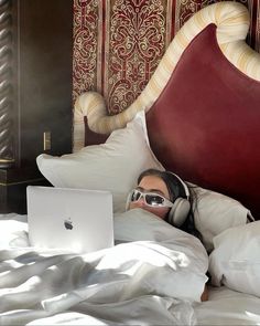 a man laying in bed with headphones on using a laptop