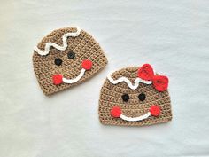 two crocheted hats with red bows are on a white surface, one has a smiling face and the other has a bow