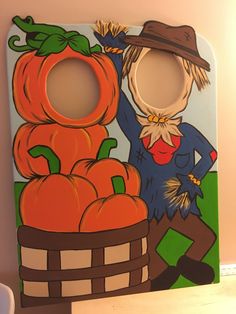 a painting of a scarecrow with pumpkins in a basket on the wall next to it