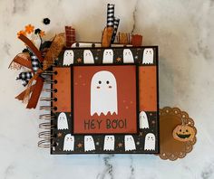 a scrapbook decorated with halloween ghostes and pumpkins is sitting on a marble surface