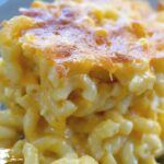 a close up view of macaroni and cheese on a blue plate with a fork