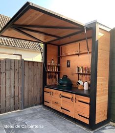 an outdoor kitchen is built into the side of a wooden building with black counter tops