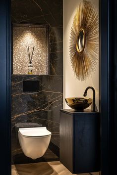 a modern bathroom with black and gold decor on the wall above the toilet is an art piece