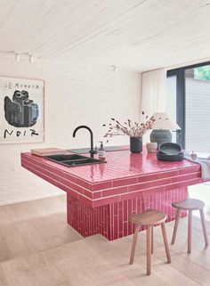 a kitchen with red counter tops and stools next to an island in the middle