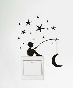 a little boy sitting on top of a wall next to a light switch box with stars