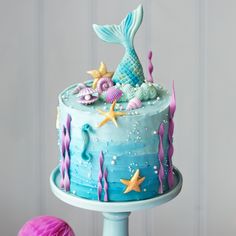 there is a blue cake with mermaid decorations on it