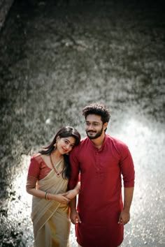 a man and woman standing next to each other in front of a body of water