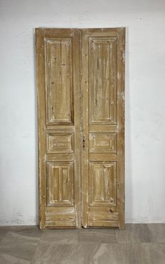 an old pair of wooden doors sitting on top of a hard wood floor next to a white wall