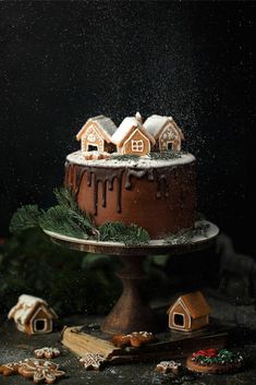 there is a cake with icing and houses on the top, surrounded by cookies