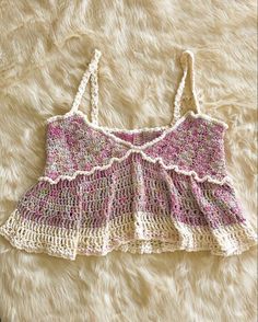 a pink and white crocheted top laying on a furry surface