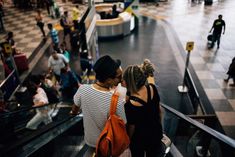 two people are kissing on an escalator at the airport while waiting for their luggage