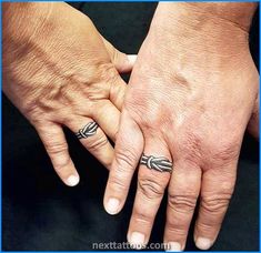 two people holding hands with tattoos on their fingers