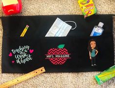 a black bag with an apple, pencils, and other school supplies on it